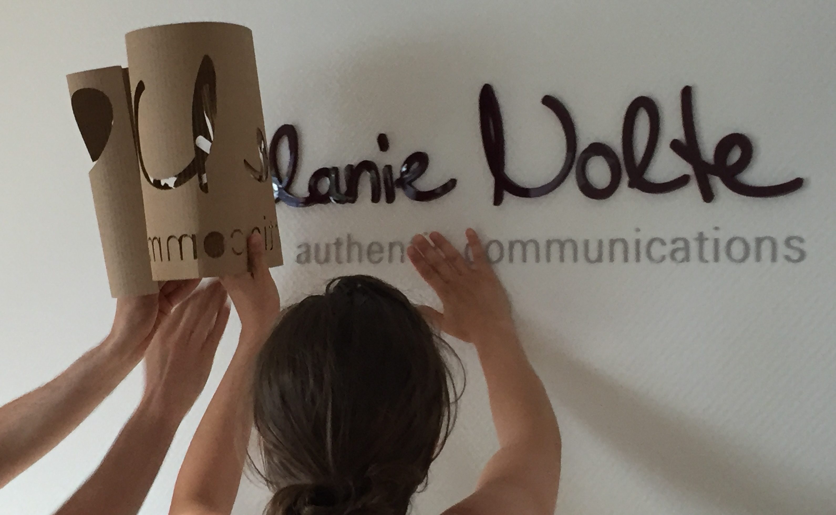 Der Schriftzug Melanie Nolte authentic communications wird an eine Wand montiert